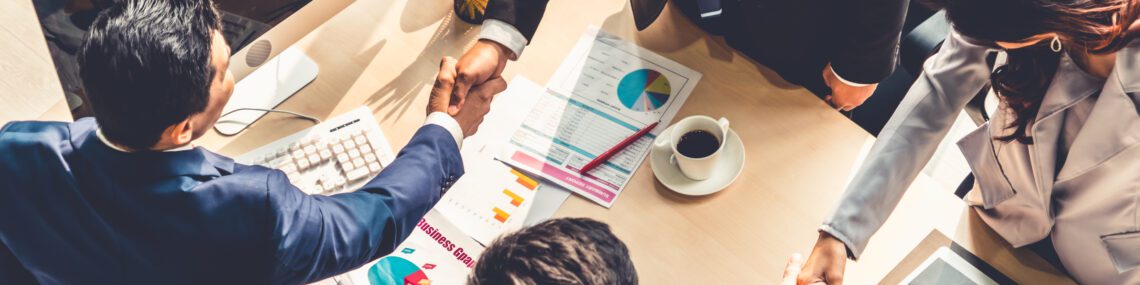 Group business people handshake at meeting table in office together with confident shot from top view . Young businessman and businesswoman workers express agreement of a merger and investment deal.