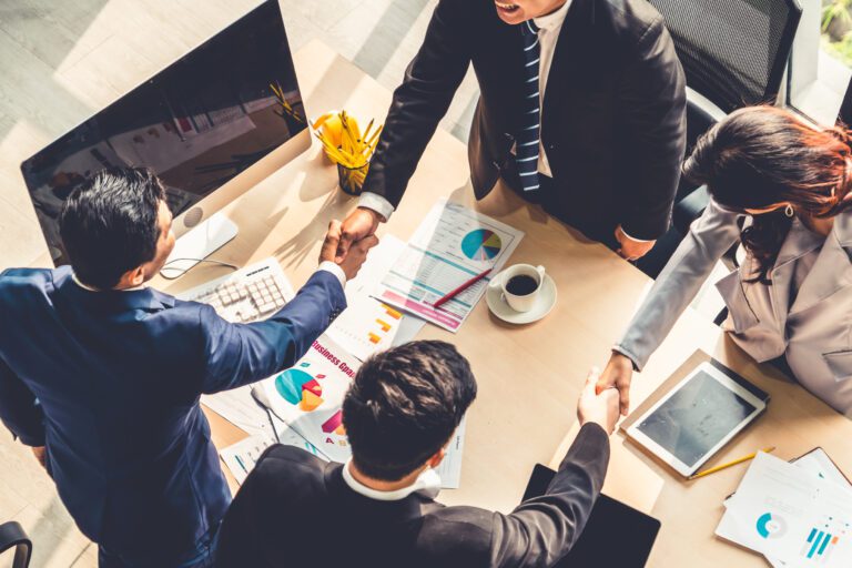 Group business people handshake at meeting table in office together with confident shot from top view . Young businessman and businesswoman workers express agreement of a merger and investment deal.