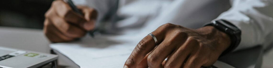 Man reviewing contract and preparing for disnature with laptop and calculator on desktop