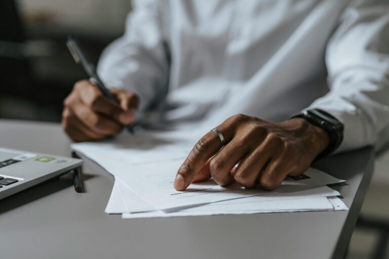 Man reviewing contract and preparing for disnature with laptop and calculator on desktop