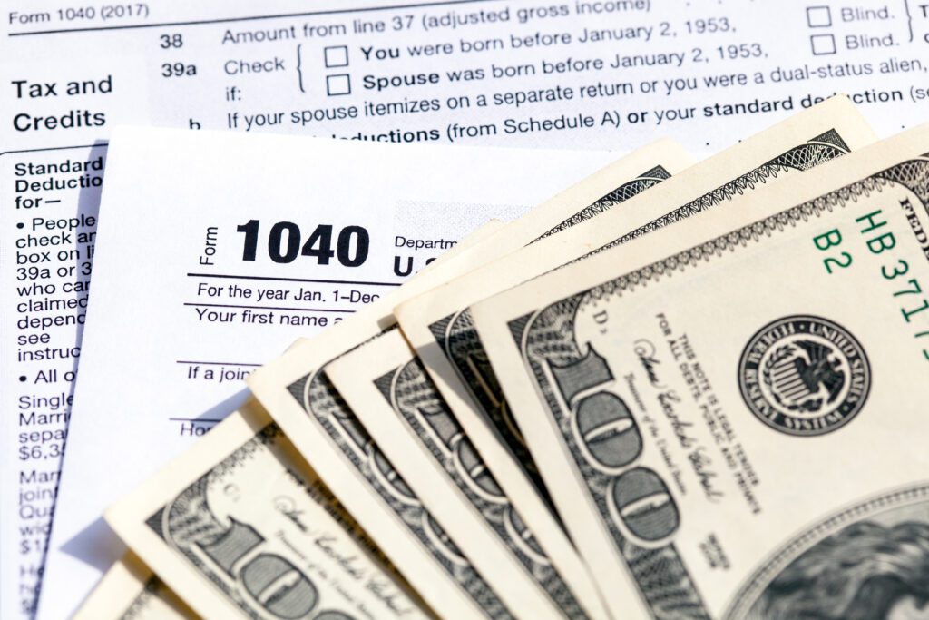 USA 1040 Individual Income Tax Return Form with one hundred dollar bills. Close-up