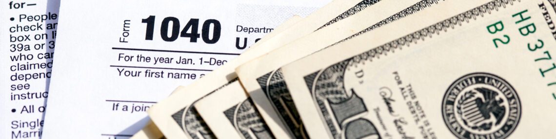 USA 1040 Individual Income Tax Return Form with one hundred dollar bills. Close-up