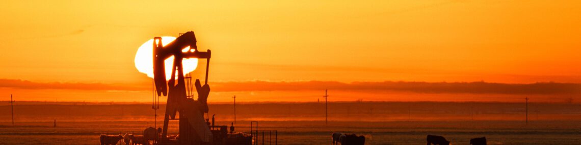 Silhouette of oil pump at sunrise with cattle