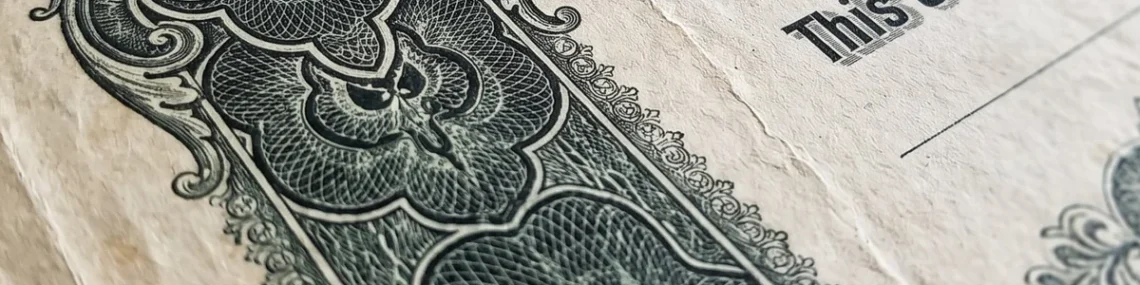 Close-up of a vintage engraved stock certificate with ornate green scrollwork border