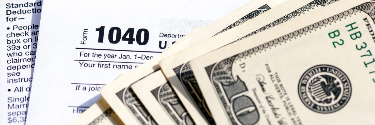 USA 1040 Individual Income Tax Return Form with one hundred dollar bills. Close-up