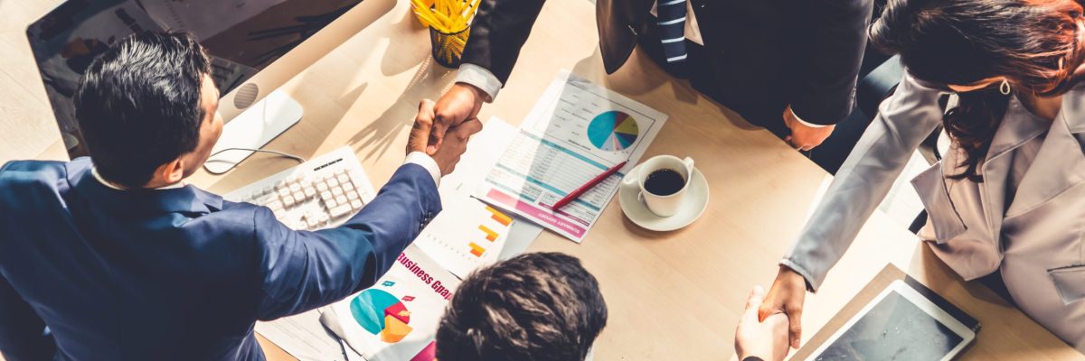 Group business people handshake at meeting table in office together with confident shot from top view . Young businessman and businesswoman workers express agreement of investment deal. Group business people handshake at meeting table in office together with confident shot from top view . Young businessman and businesswoman workers express agreement of a merger and investment deal.