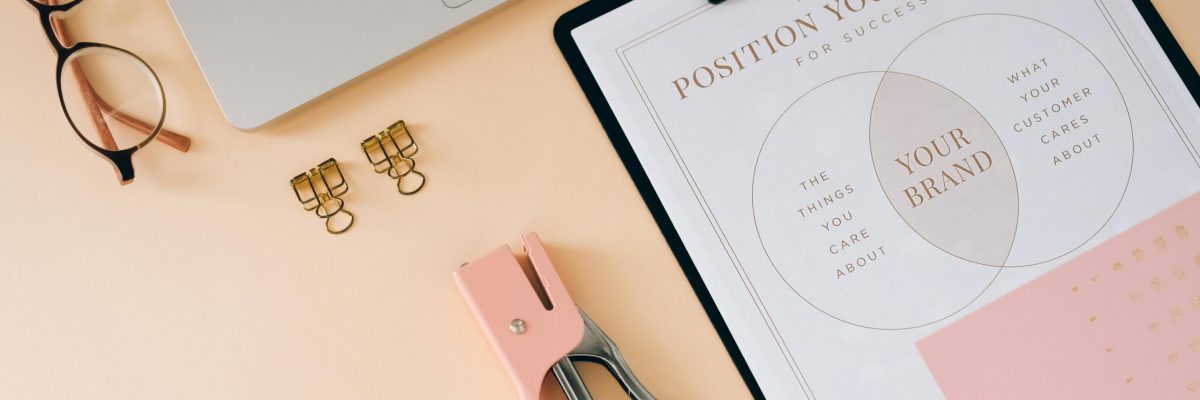 Brand position strategy documents on desk with laptop