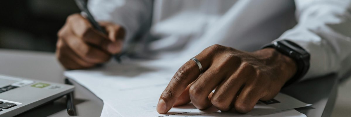 Man reviewing contract and preparing for disnature with laptop and calculator on desktop