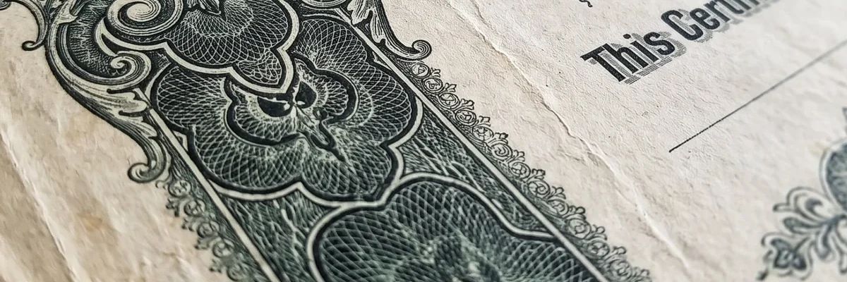 Close-up of a vintage engraved stock certificate with ornate green scrollwork border